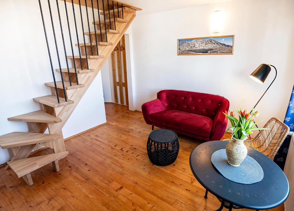 a living room with a red couch and a table at Tatraview House in Veľká Lomnica