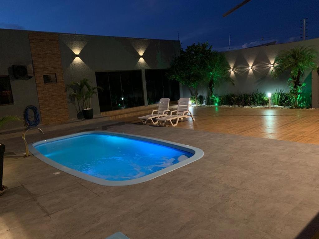 a large swimming pool with chairs and a building at Sobrado com 5 suítes para temporada e show rural in Cascavel