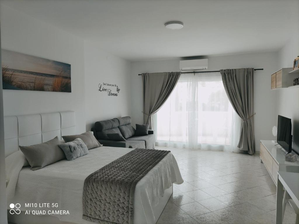 1 dormitorio con cama y ventana grande en BenalSuite estudio, piscina y playa en BenalBeach, Benalmadena en Benalmádena