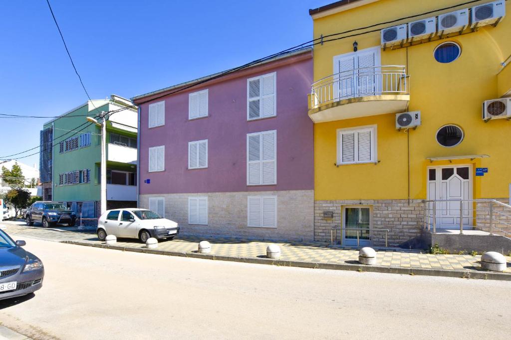een geel en roze gebouw aan de straatkant bij Apartment Amethist in Biograd na Moru