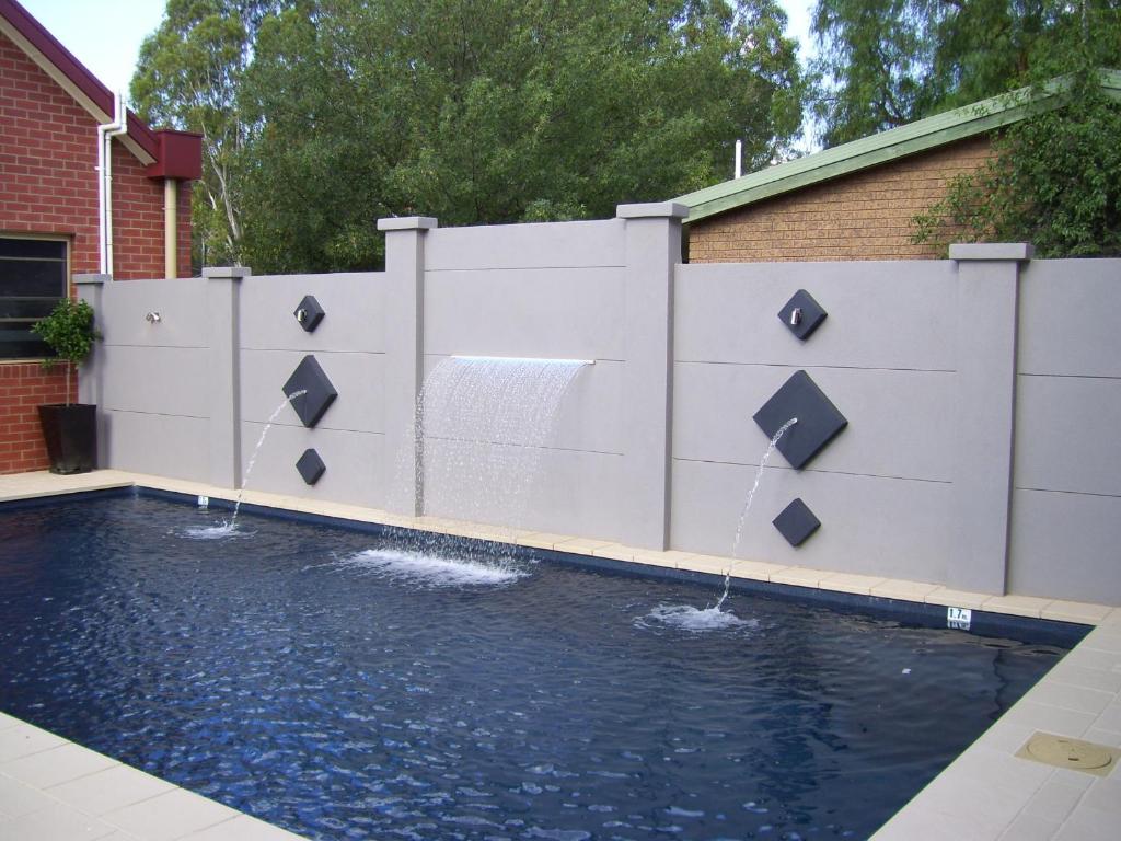 a swimming pool with a fence and waterfalls at Murray Waters Motor Inn & Apartments in Koondrook