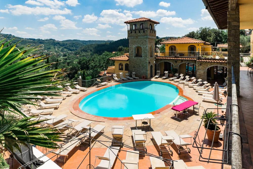 een resort met een zwembad en stoelen en een toren bij Villa La Malva in Poggio alla Malva