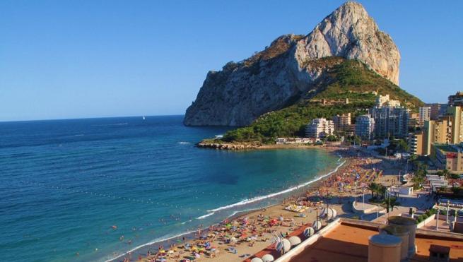 a beach with a bunch of people and the ocean at Sol y Mar in Calpe