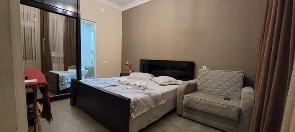 een slaapkamer met een bed en een stoel bij Guest House Kldiashvili in Batoemi