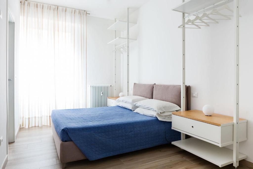 - une chambre blanche avec un lit doté d'un couvre-lit bleu dans l'établissement La Casa di Greta, à Vérone