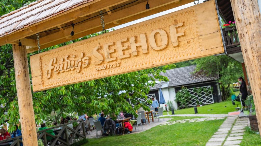 un panneau indiquant un restaurant dans un parc dans l'établissement Seehof Feidig, à Velden am Wörther See