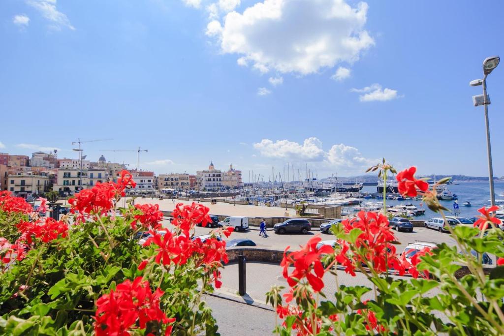 een uitzicht op een haven met rode bloemen op de voorgrond bij Casa Adele b&b in Pozzuoli