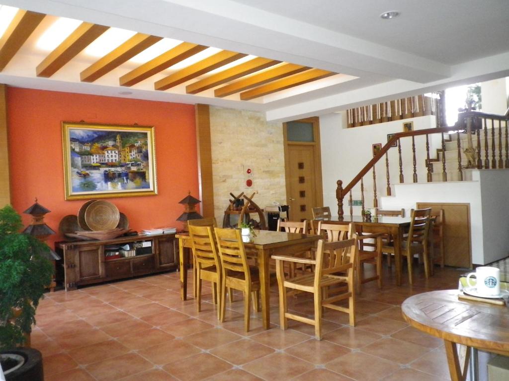 a dining room with orange walls and wooden tables and chairs at Mamalulu Hostel in Kenting