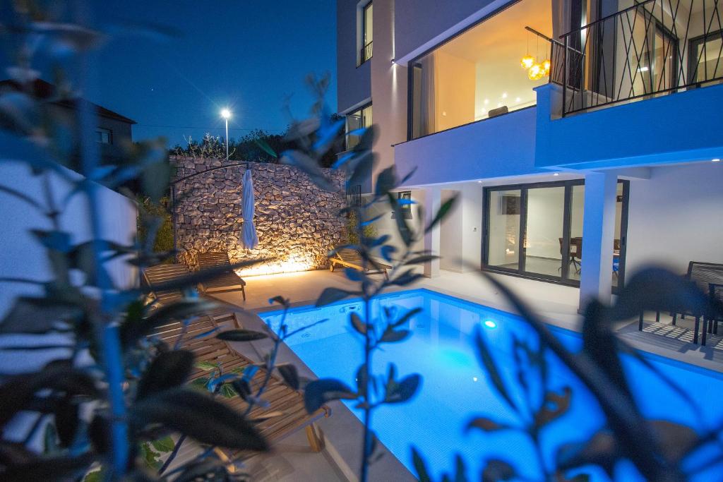 a house with a swimming pool at night at Villa Sea Silhouette in Žman