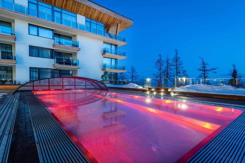 a swimming pool with red lights in front of a building at Studio A205 Hrebienok resort Starý Smokovec with garage in Vysoke Tatry - Stary Smokovec