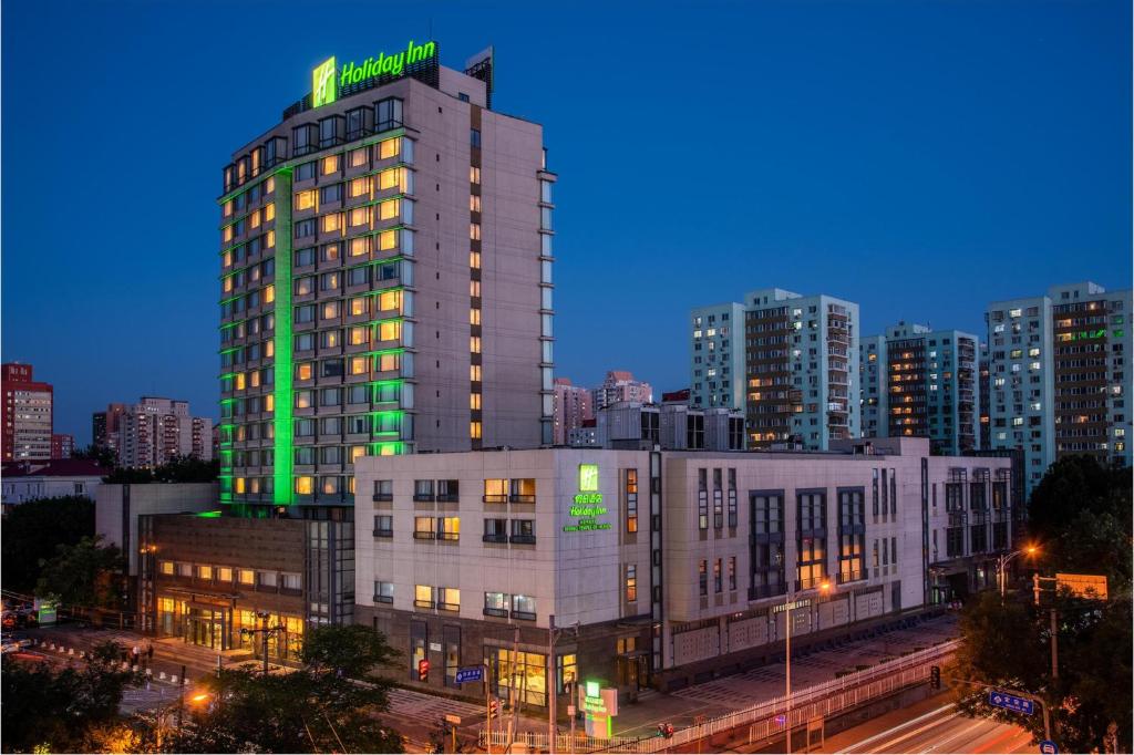 un edificio alto con una señal verde encima en Holiday Inn Temple Of Heaven Beijing, an IHG Hotel en Beijing