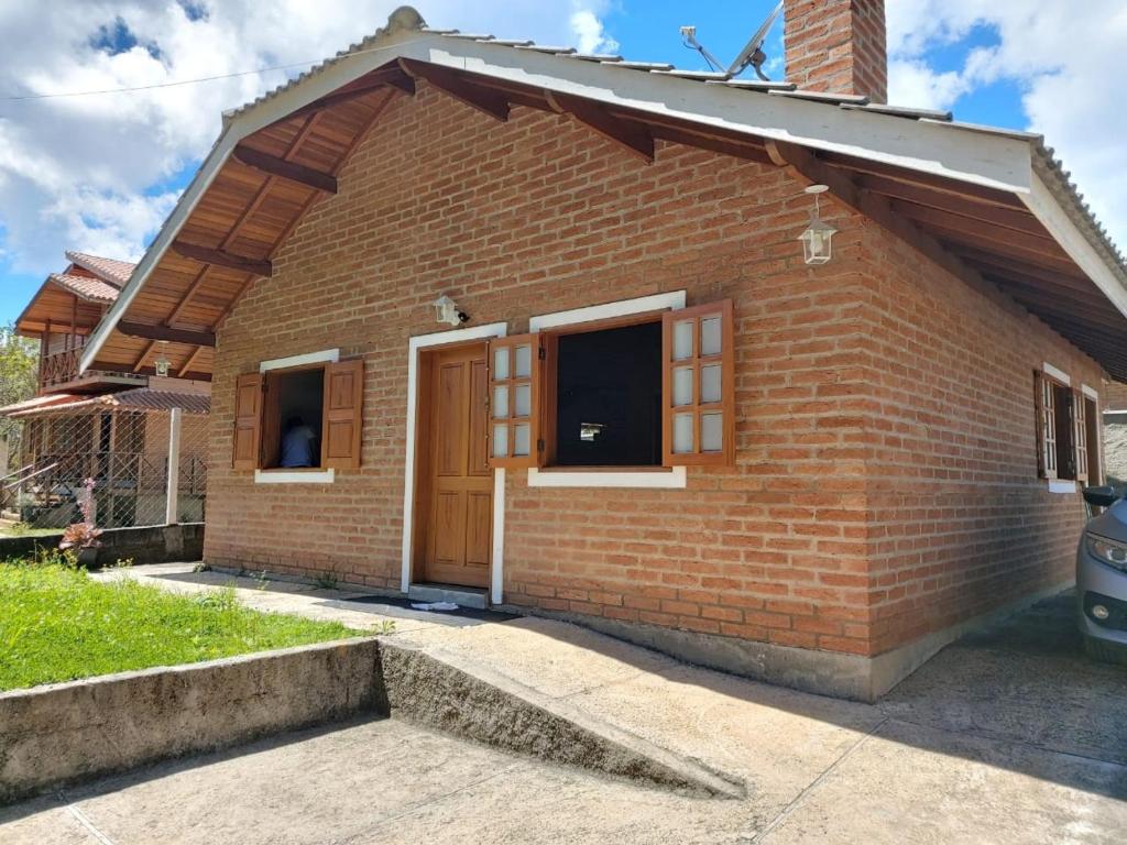 ceglany dom z brązowymi drzwiami i oknami w obiekcie Chalé da Mina w mieście Monte Verde