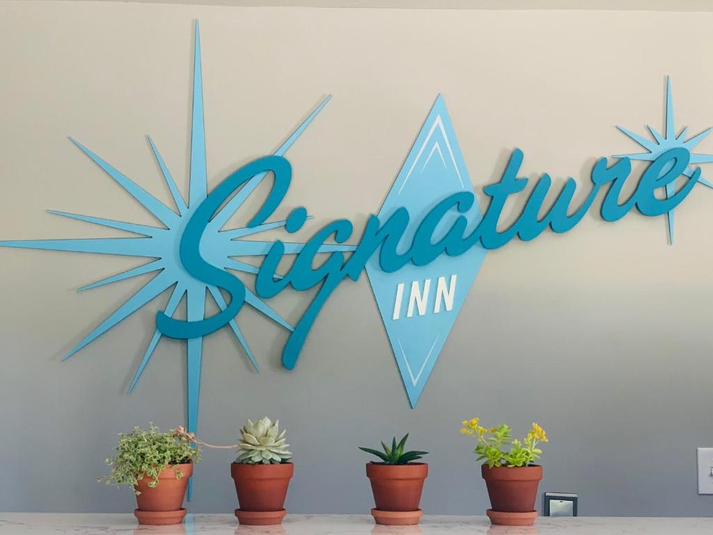 a blue sign on a wall with potted plants at Signature Inn Santa Clara in Santa Clara