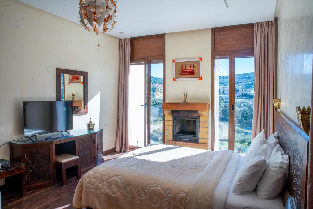 a bedroom with a bed with a fireplace and a television at Dar Zayane in Khenifra
