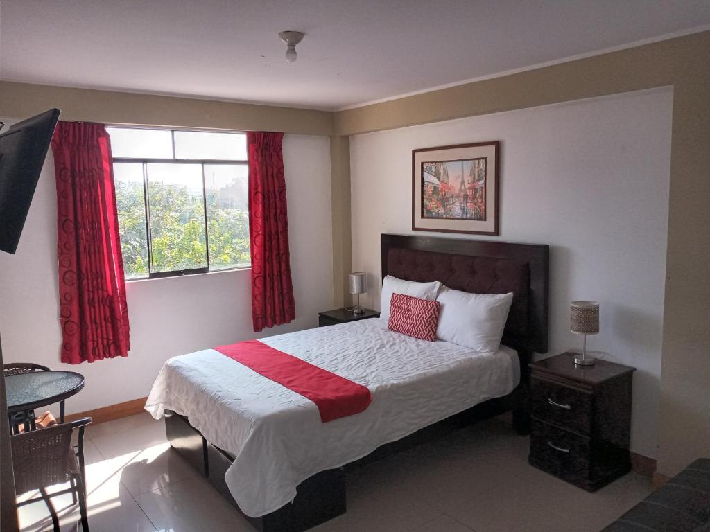 um quarto com uma cama e uma janela com cortinas vermelhas em Pisco Hotel Corina em Pisco