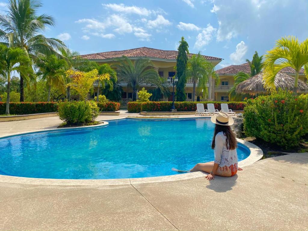 a little girl sitting next to a swimming pool at La Ensenada Beach Resort in Tela