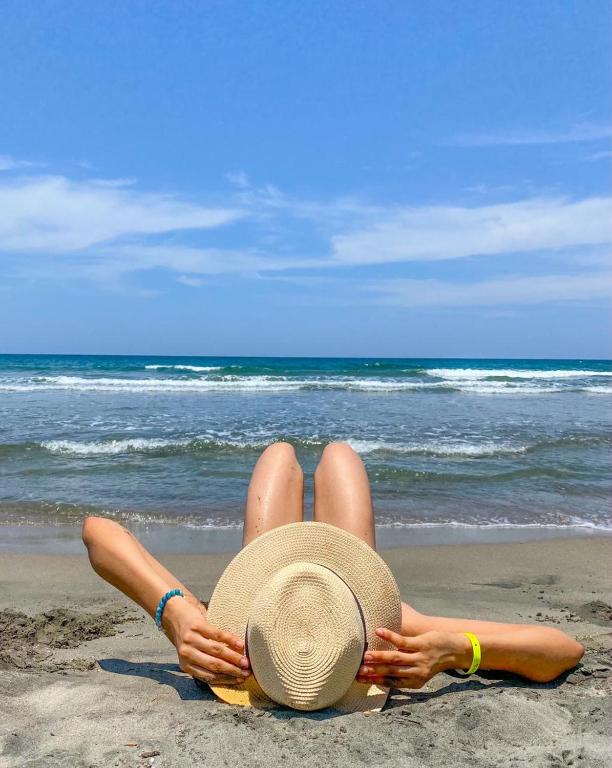 a woman laying on the beach with a hat at La Ensenada Beach Resort in Tela