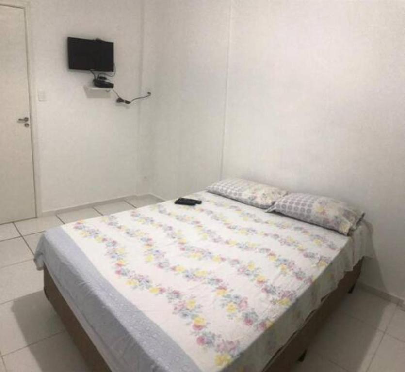 Cama en habitación con TV en la pared en Apartamento em Santos en Santos