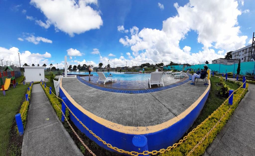 a pool at a resort with people sitting in chairs at Apartamentos y Piscina a 3 min del Parque Cafe in Montenegro