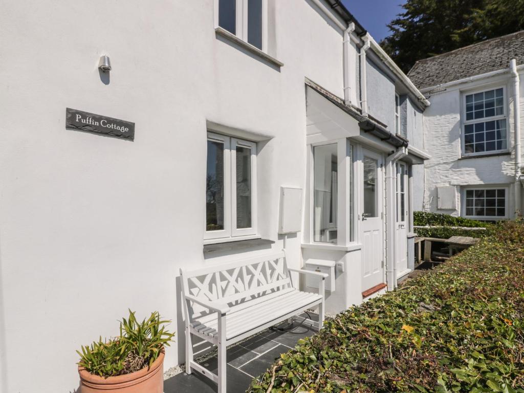 a white house with a bench outside of it at Puffin Cottage in Truro