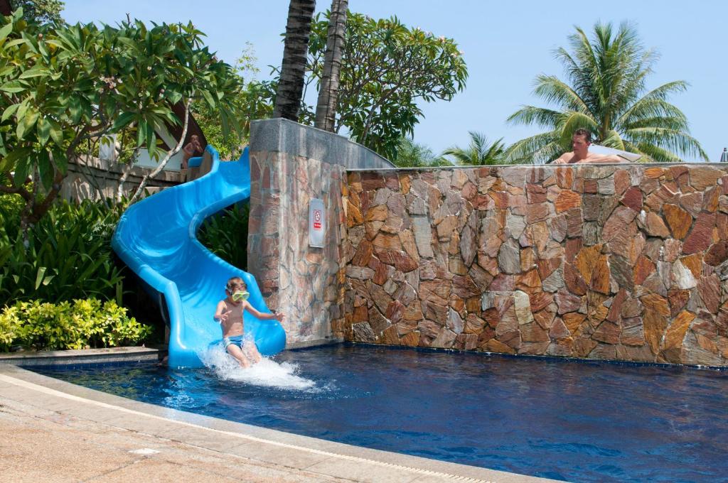 Ein junges Mädchen auf einer Wasserrutsche im Pool in der Unterkunft Rawi Warin Resort And Spa - SHA Extra Plus in Ko Lanta