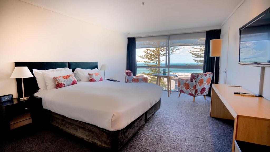 Scenic Hotel Te Pania في نابيير: غرفة فندقية بسرير وإطلالة على المحيط