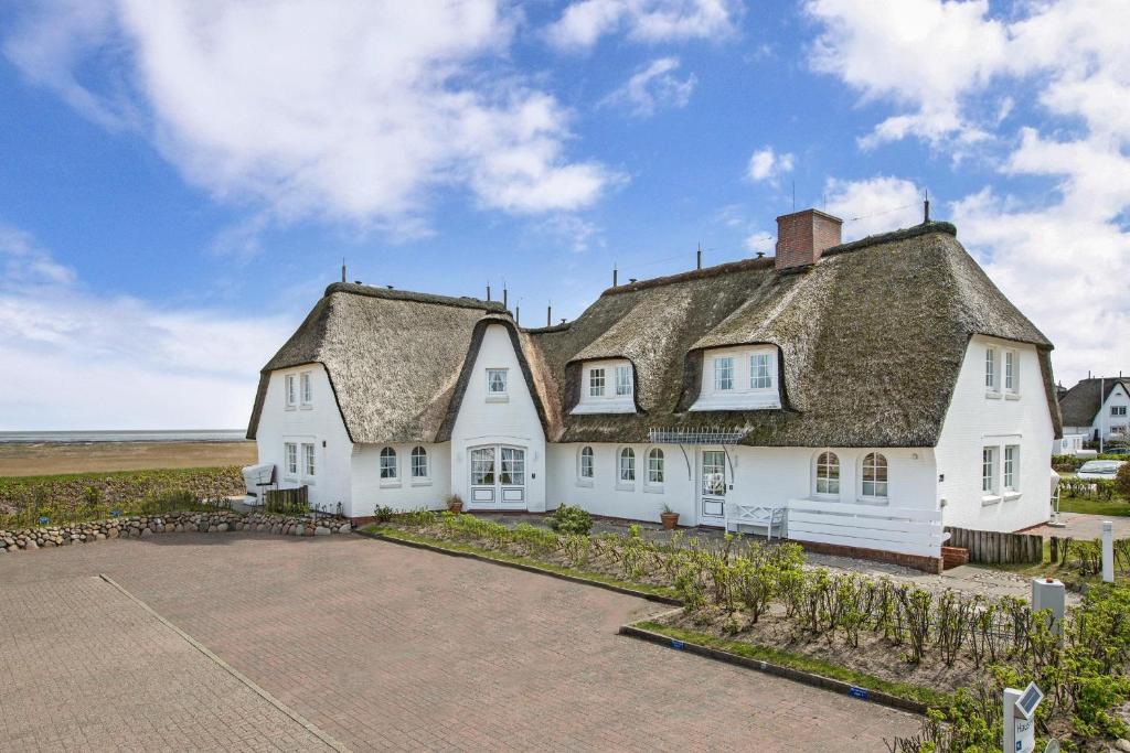 una grande casa bianca con tetto di paglia di Haus Heefkant Whg 10 a Rantum