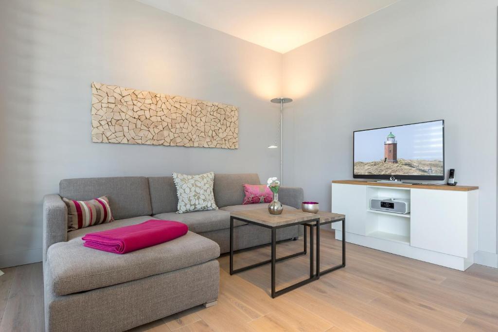 uma sala de estar com um sofá e uma televisão em Neue Mitte Whg 12 em Westerland