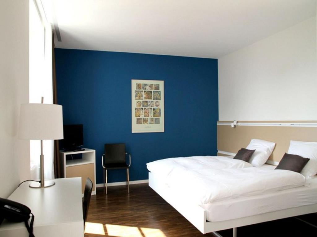 una camera da letto con un letto e una parete blu di Auberge de Prangins a Prangins