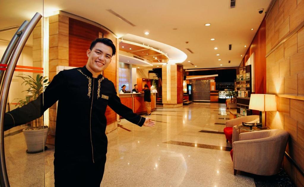 Greenhills Elan Hotel Modern في مانيلا: رجل واقف في بهو الفندق
