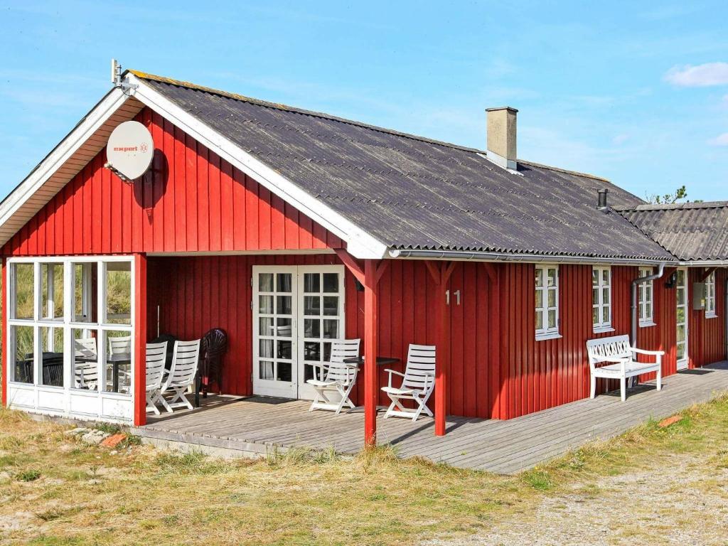 um celeiro vermelho com cadeiras num deque de madeira em 6 person holiday home in Hvide Sande em Nørre Lyngvig