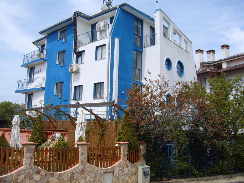 a blue and white building behind a fence at Andi Hotel in Chernomorets