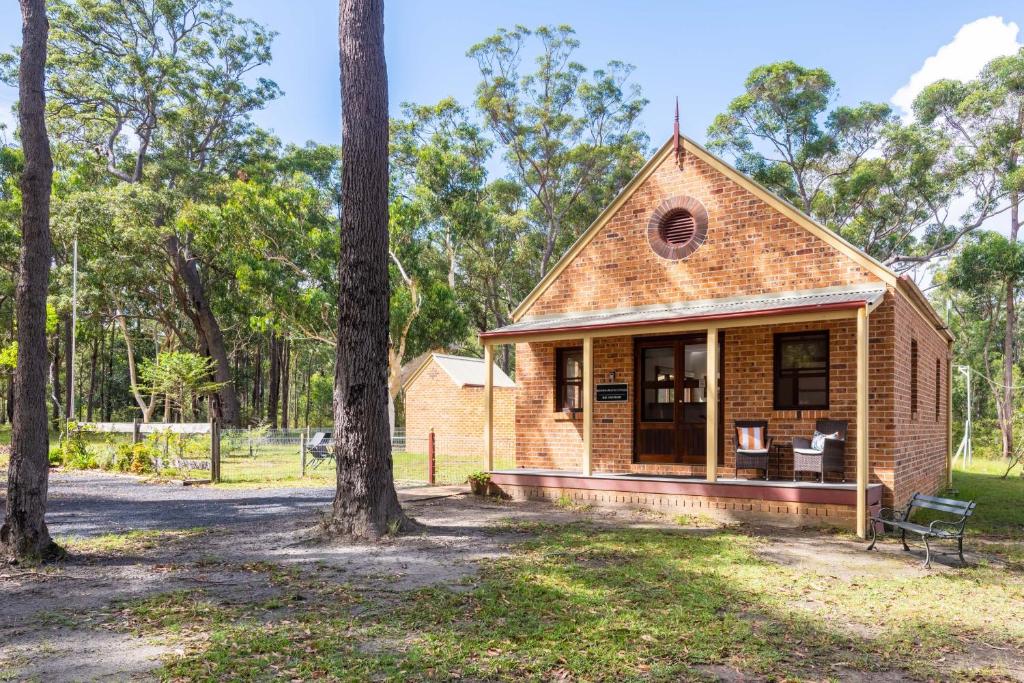 ein winziges Haus im Wald mit einer Veranda in der Unterkunft Bay and Bush Cottages Jervis Bay in Huskisson