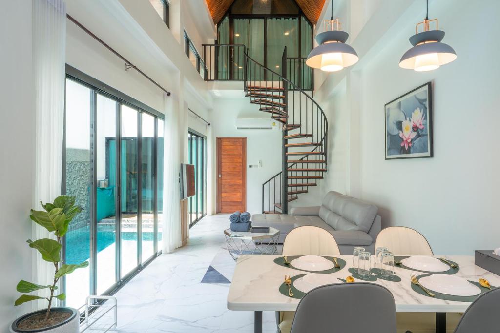 a living room with tables and chairs and a staircase at Poonsiri Varich Pool Villa Aonang in Ao Nang Beach