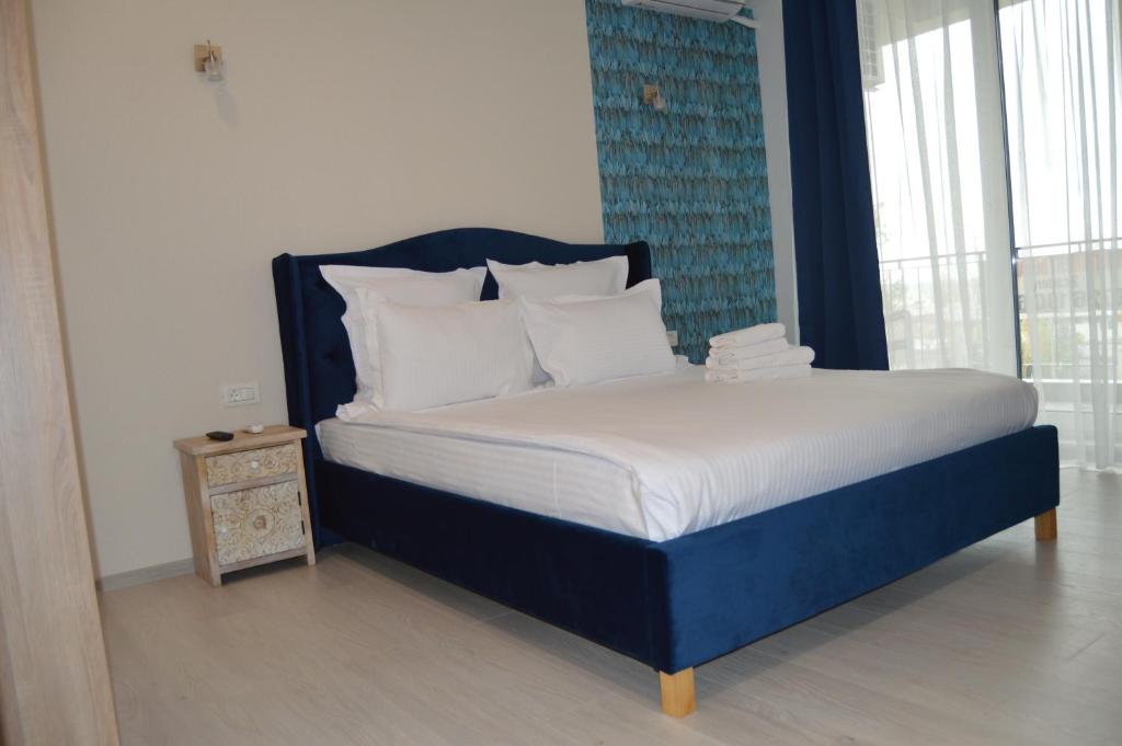 a bed with a blue headboard and white pillows at Velier Apartments 38 and 49 in Mamaia
