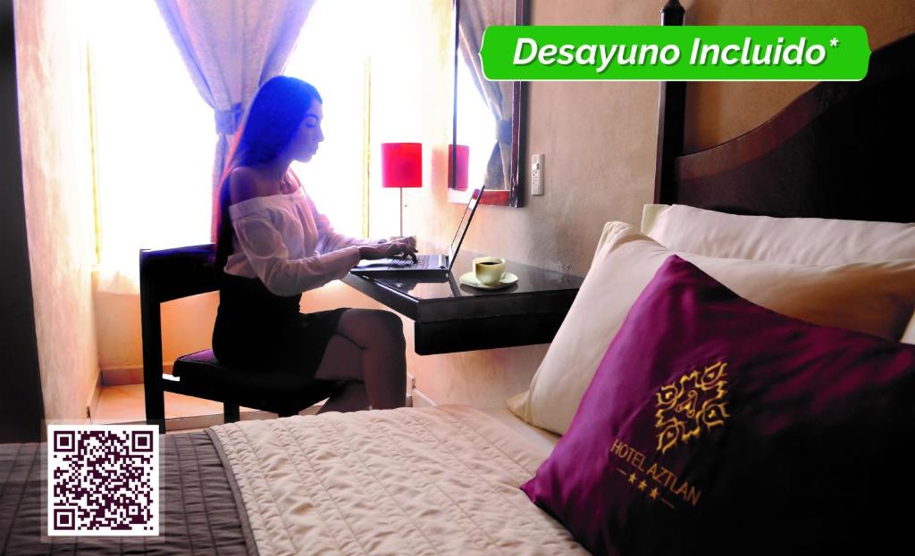 uma mulher sentada numa secretária com um portátil num quarto de hotel em Hotel Aztlan em Jalisco
