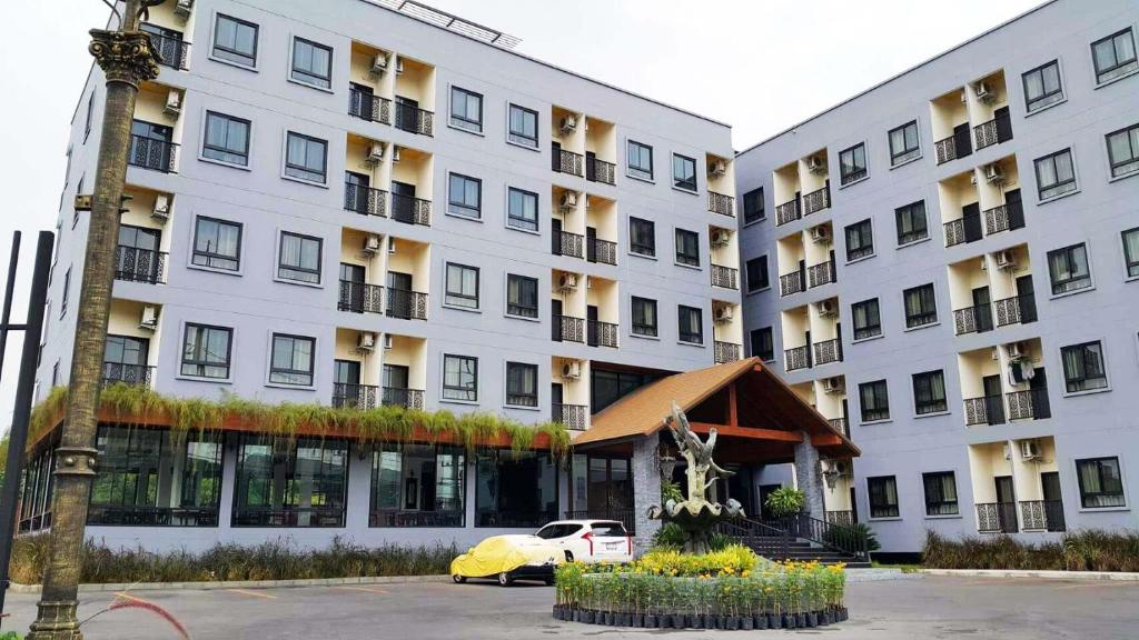 巴吞他尼Hotel IYA的一座白色的大建筑,前面有一辆汽车