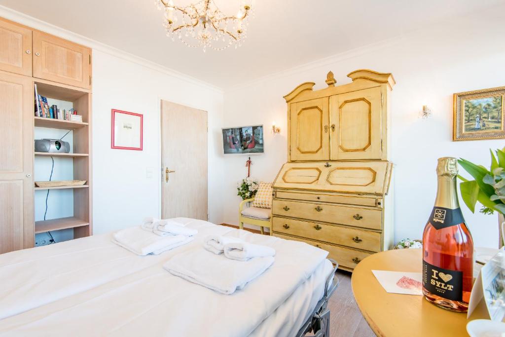 een slaapkamer met een bed, een dressoir en een fles wijn bij Duenenhof zum Kronprinzen Whg 107 in Wenningstedt