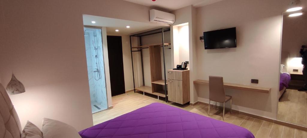 a bedroom with a purple bed and a tv at Sonia Hotel & Suites in Kos Town