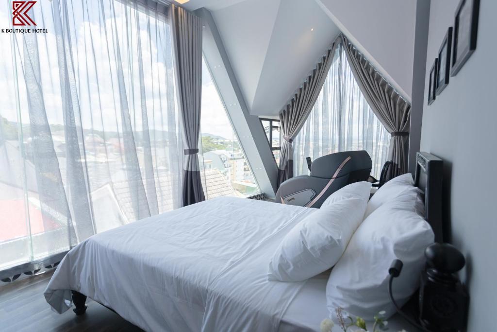 sypialnia z białym łóżkiem i dużymi oknami w obiekcie K Boutique Hotel w mieście Da Lat