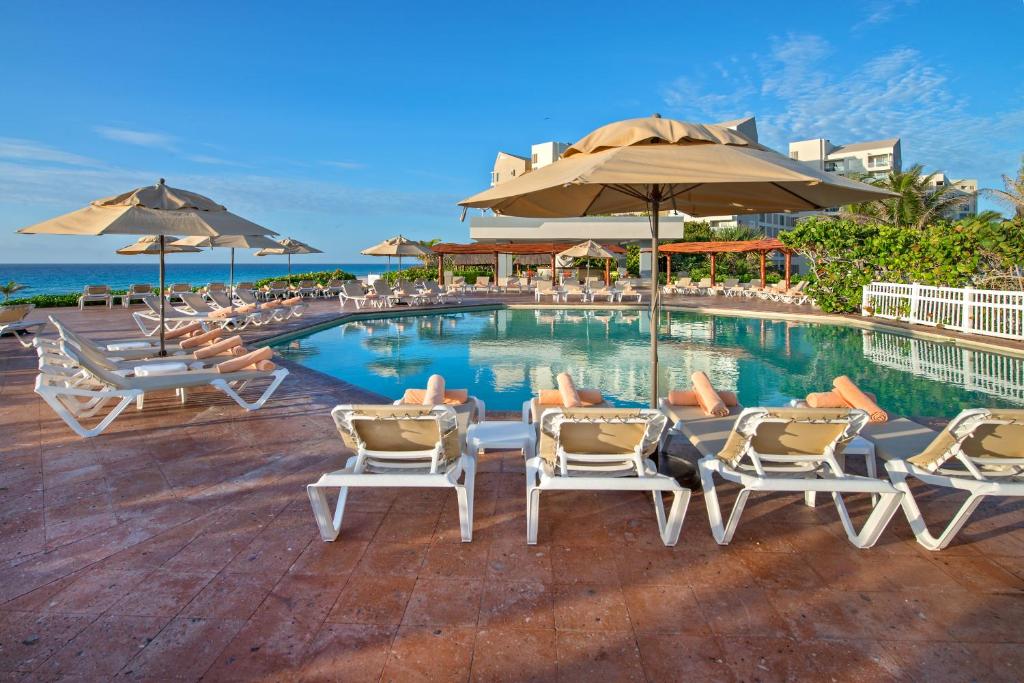 una piscina con sedie a sdraio e ombrelloni di State of the Art Condos en la mejor Playa de Cancun frente a PLAZA LA ISLA a Cancún