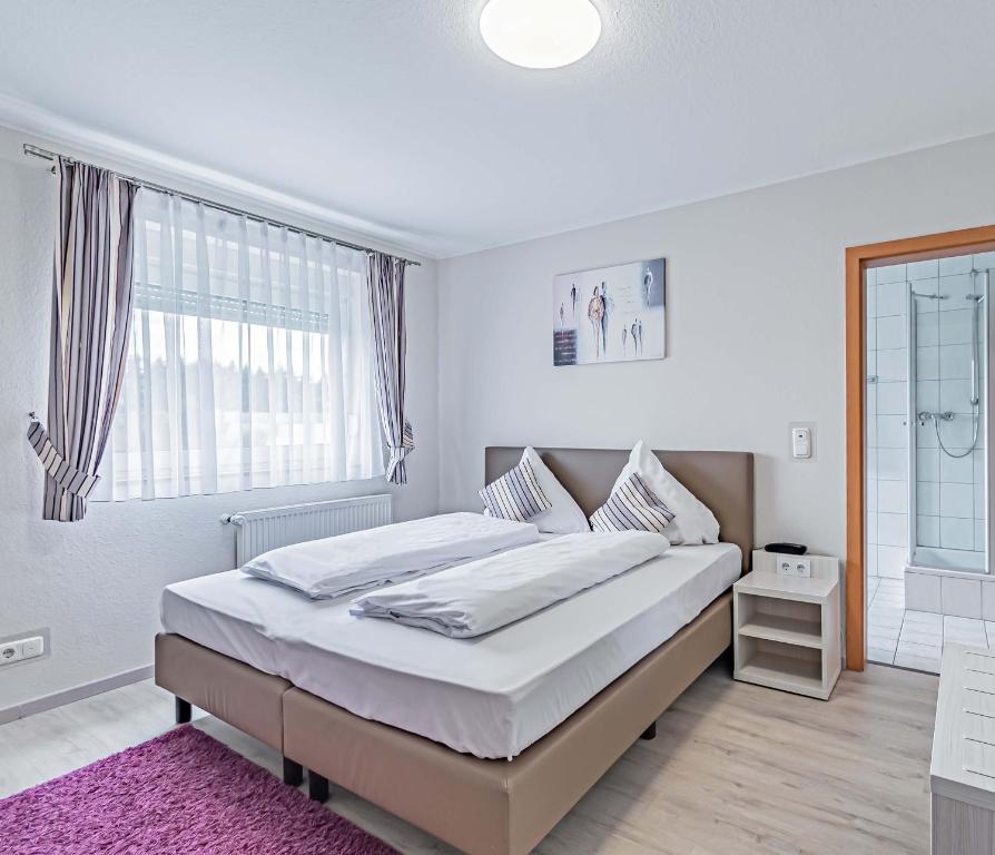 a white bedroom with a large bed and a window at Hotel Tannenblick in Bad Vilbel