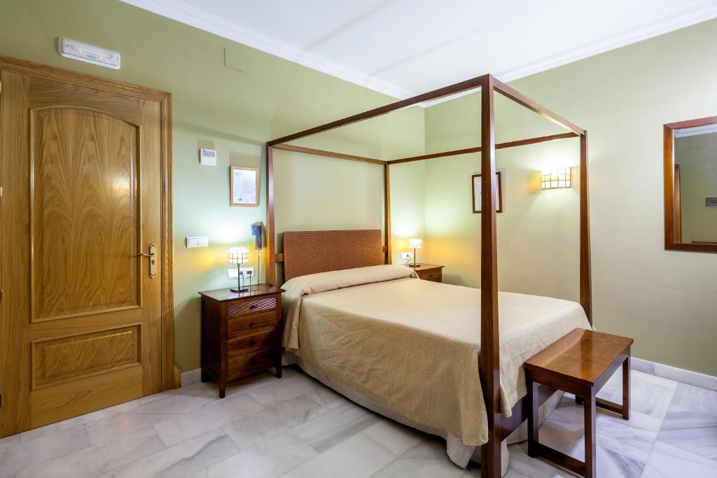 a bedroom with a canopy bed and a wooden door at Hotel Las Casas del Duque in Osuna