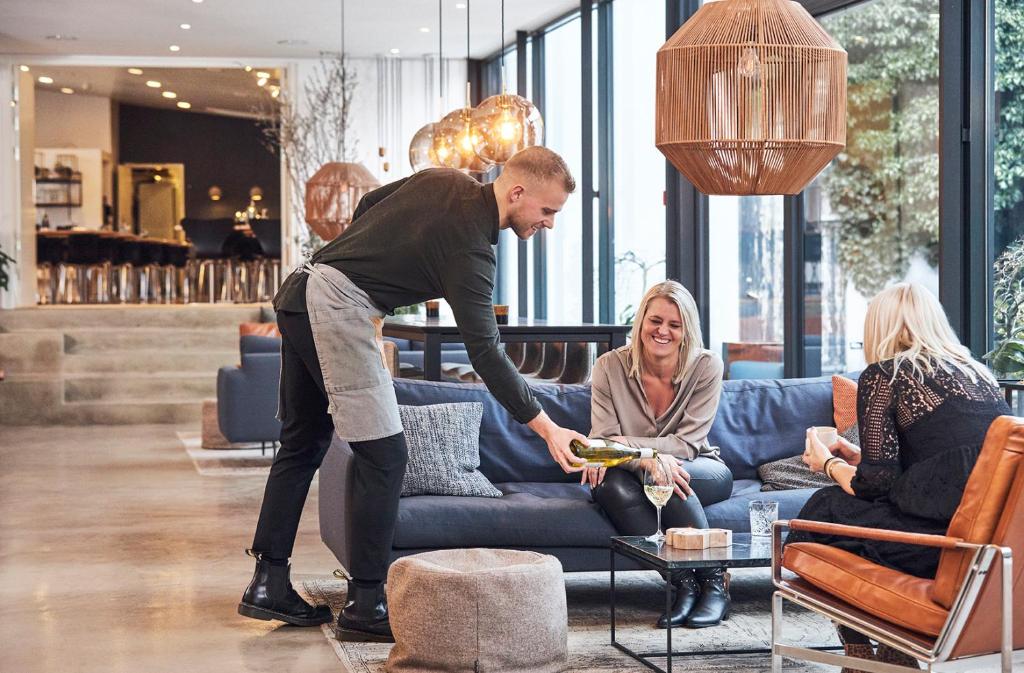 a man standing in front of a woman in a living room at Hotel Oasia Aarhus City in Aarhus