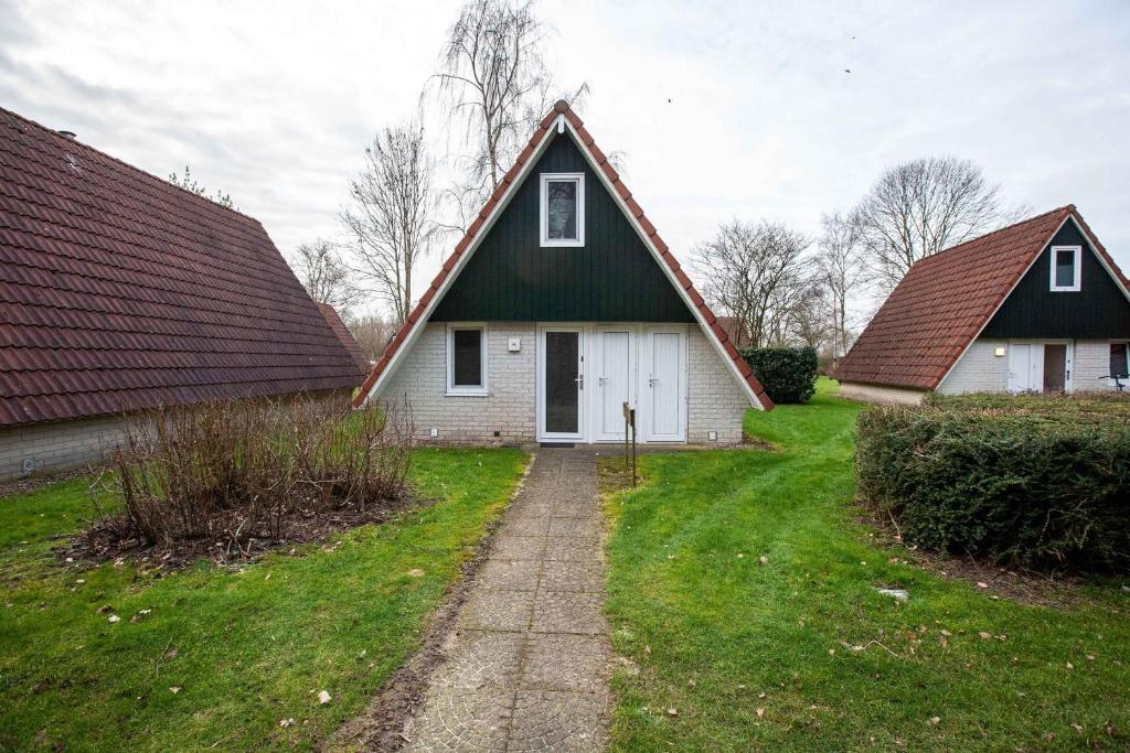 dom z zielonym dachem i dwoma budynkami w obiekcie Stijlvolle vakantiewoning just for holliday w mieście Gramsbergen
