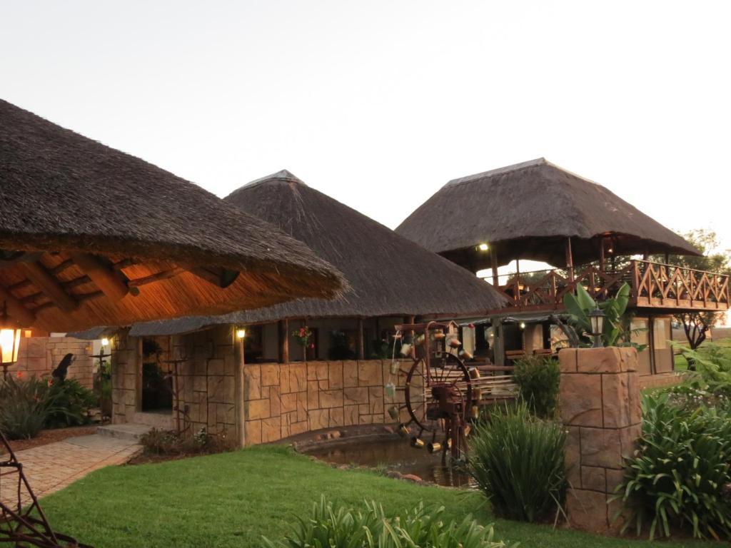 a building with thatched umbrellas and a pool at Guinea Feather Country Lodge & Spa in Groblersdal