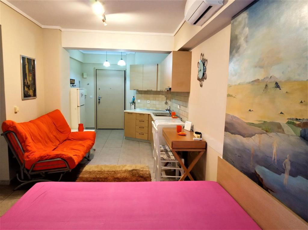 a living room with an orange couch and a kitchen at Tzikas apARTments in Thessaloniki