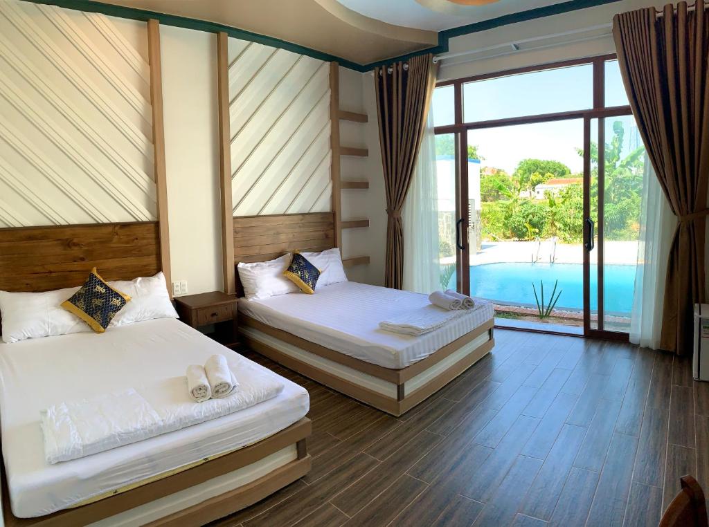 twee bedden in een kamer met uitzicht op een zwembad bij Gia An Hung Guest House in Mũi Né