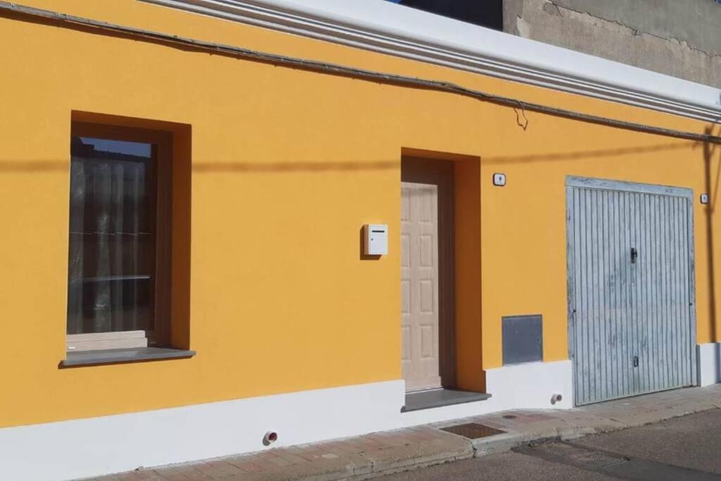 ein gelbes Gebäude mit zwei Fenstern und einer Tür in der Unterkunft Casa Aida in Nurachi
