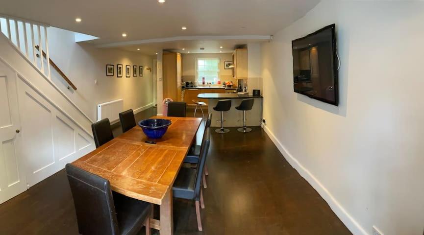 einen Esstisch mit Stühlen und einen TV an der Wand in der Unterkunft Luxury Central London 3 Bedroom Family House in London